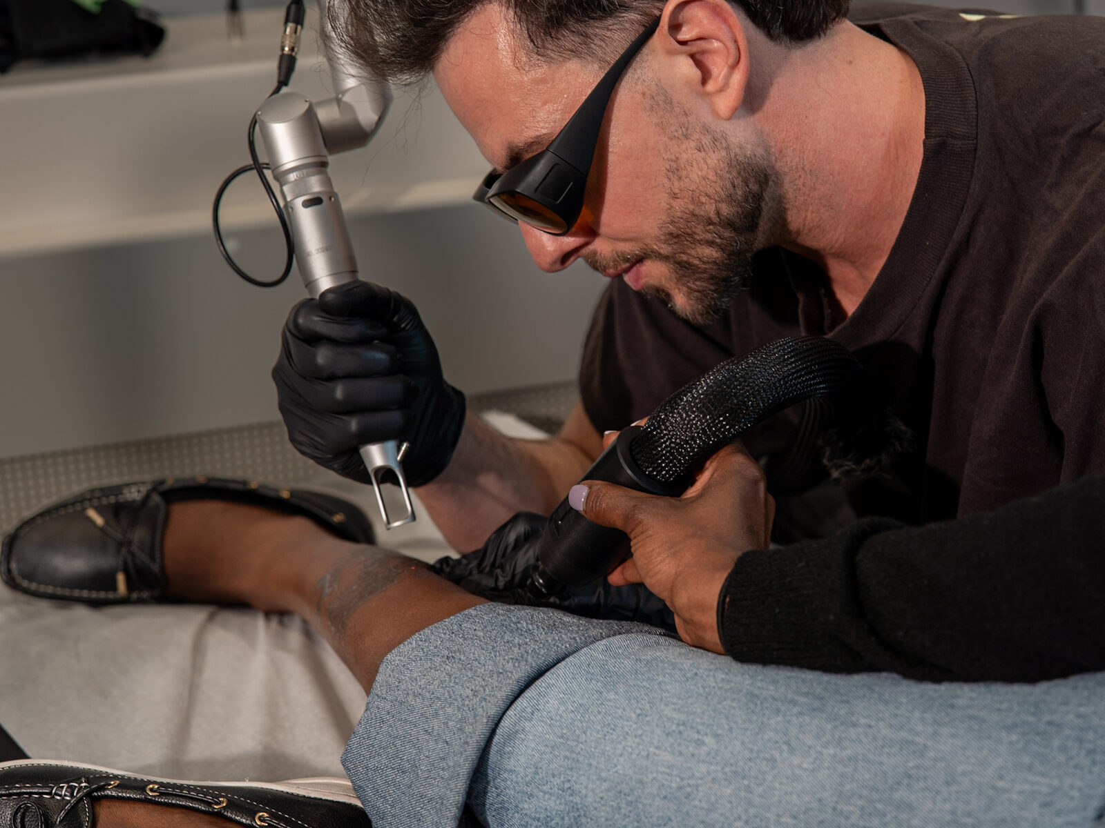 Vlad performing laser tattoo removal on a client's leg at Rico Clinic
